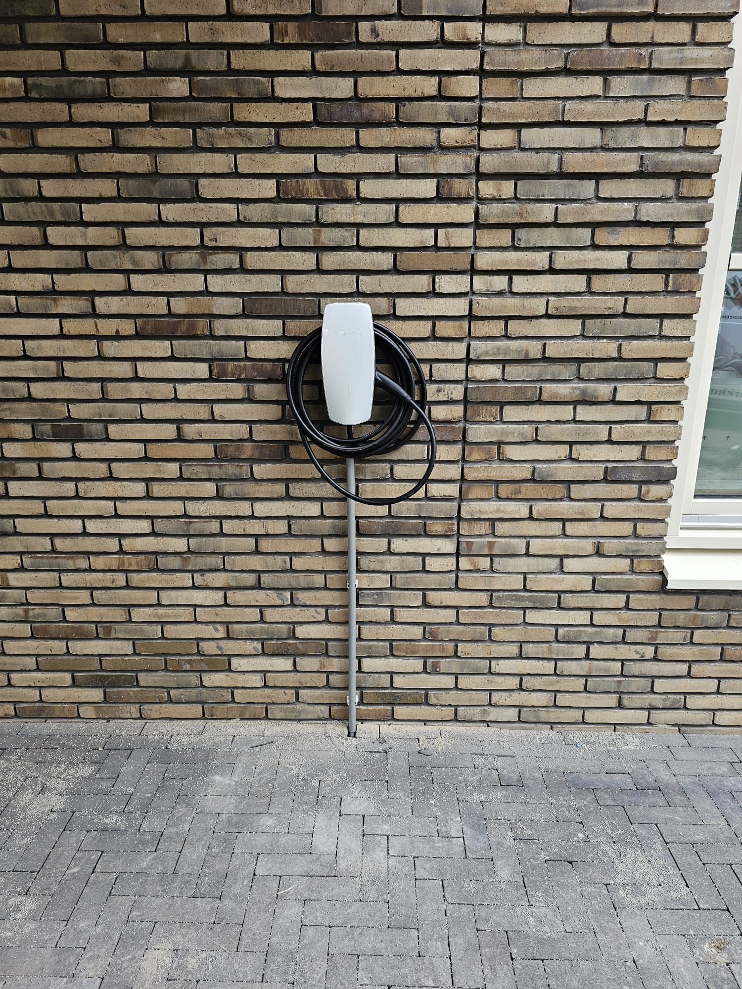 Tesla laadpaal gemonteerd aan een bakstenen woning